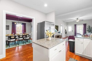 A modern kitchen with white cabinets, a granite countertop, and a stainless steel refrigerator. - Backyard Hangout Firepit, Giant Connect 4 & BBQ (Raleigh)