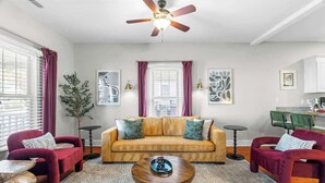 A living room with a sofa, two armchairs, a coffee table, a ceiling fan, and artwork on the walls. - Backyard Hangout Firepit, Giant Connect 4 & BBQ (Raleigh)