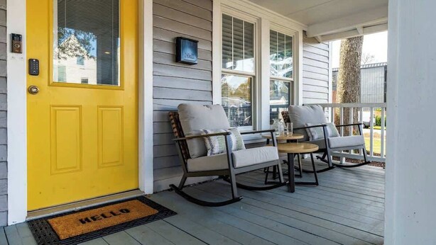 A porch with a yellow door, two rocking chairs, and a small table. - Backyard Hangout Firepit, Giant Connect 4 & BBQ (Raleigh)