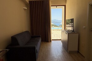 Ein Zimmer mit einer Couch, einem Fernseher auf einem Schrank und einer Tür zu einem Poolbereich.