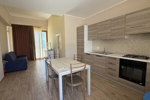 Une cuisine moderne avec des meubles en bois, une table à manger avec des chaises et un canapé dans l’espace salon.