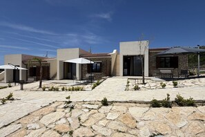 A modern building with stone and concrete exterior, outdoor seating, and a clear sky. - Sea-view apartment with a pool (Telegrafo)