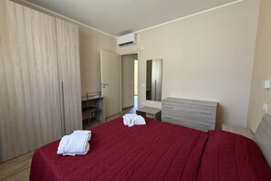 Une chambre à coucher avec un lit, une armoire, un bureau et un miroir.