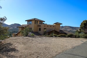 A two-story house with a flat roof, a balcony, and a driveway.