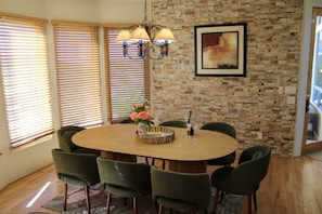 A dining area with a brick wall, a round table, and green chairs.