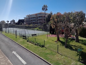 A multi-story hotel with balconies, a tennis court, and a playground. - Sea and Sun (Saint-Laurent-du-Var)