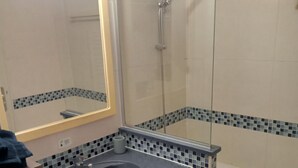 A bathroom with a sink, mirror, shower, and tiled walls. - Sea and Sun (Saint-Laurent-du-Var)