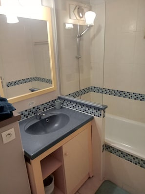 A bathroom with a sink, mirror, shower, and tiled walls. - Sea and Sun (Saint-Laurent-du-Var)