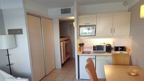 A compact kitchen with a microwave, toaster, and coffee maker. There is a dining area with a table and chairs. - Sea and Sun (Saint-Laurent-du-Var)