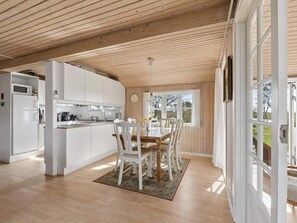 A modern kitchen with white cabinets and a dining area with a wooden table and chairs. - 4 Star Holiday Home in Struer (Struer)