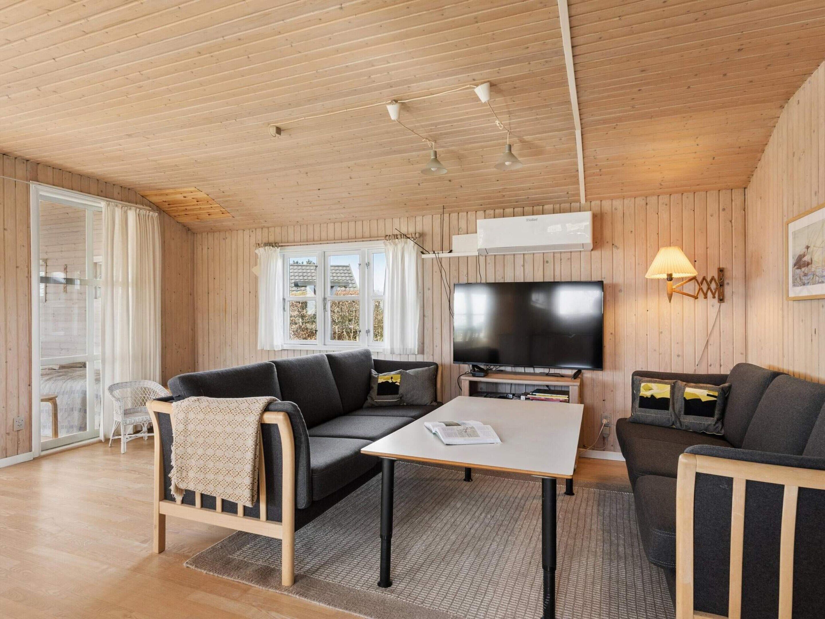 Ein gemütliches Zimmer mit einer Couch, einem kleinen Tisch, einem Fernseher und einer Lampe.