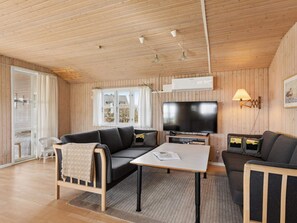 A cozy room with a sofa, a small table, a TV, and a lamp. - 4 Star Holiday Home in Struer (Struer)