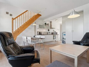 Ein modernes Wohnzimmer mit Ledersesseln, einem Holzesstisch und einer Treppe.