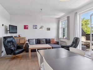 A modern living room with a sofa, chairs, a table, a TV, and artwork on the wall. - 5 Star Holiday Home in Aakirkeby (Akirkeby)
