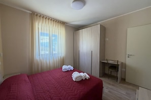 Ein Hotelzimmer mit Bett, Schreibtisch, Kleiderschrank und Tür.