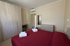 A hotel room with a bed, a desk, a wardrobe, and a mirror. - Sea-view apartment with a pool (Telegrafo)