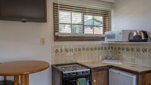 A compact kitchen with a gas stove, a microwave, and a small refrigerator. - Carriage House at Roadhouse Lodge: romantic suite, fireplace & lake-view deck (Twin Lakes)