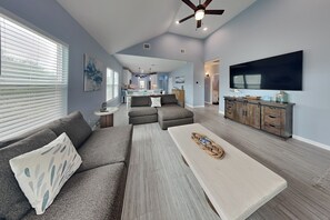 A spacious living room with a gray sectional sofa, a coffee table, and a TV mounted on the wall. - Lone Star Lookout (Rockport)