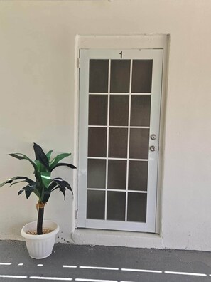 A white door with a grid pattern, a potted plant beside it, and a white wall. - Casa Bali Tropical Escape (Sabana)