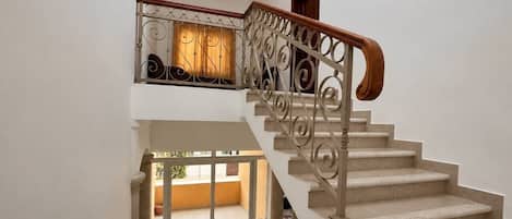 Una escalera con barandilla de madera y balaustres metálicos decorativos.