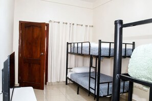 A room with bunk beds, a wooden door, and a white curtain.