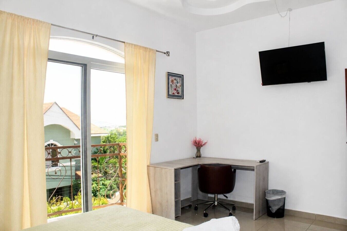 Une chambre à coucher avec un lit, un bureau, une chaise, une télévision et une fenêtre avec des rideaux.