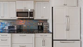 A kitchen with white cabinets, a Bosch microwave, a Krups coffee maker, and a toaster.