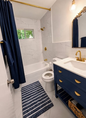 A bathroom with a bathtub, toilet, and vanity with gold fixtures. - Charming and centrally located 3-bedroom home in Austell (Austell)