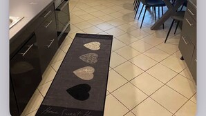 Une cuisine avec un sol carrelé, une cuisinière, une table à manger avec des chaises et une fenêtre.