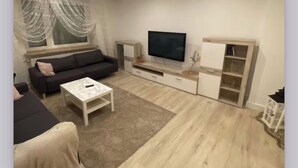 Un salon moderne avec un canapé, un téléviseur et un meuble de rangement.