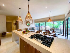 A modern kitchen with a gas stove, wooden cabinets, and pendant lights. - Selva Norte: Jungle Luxe with jaccuzi and pool (Tulum)