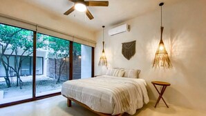 Un dormitorio con cama, ventilador de techo, lámpara colgante y vistas al exterior.