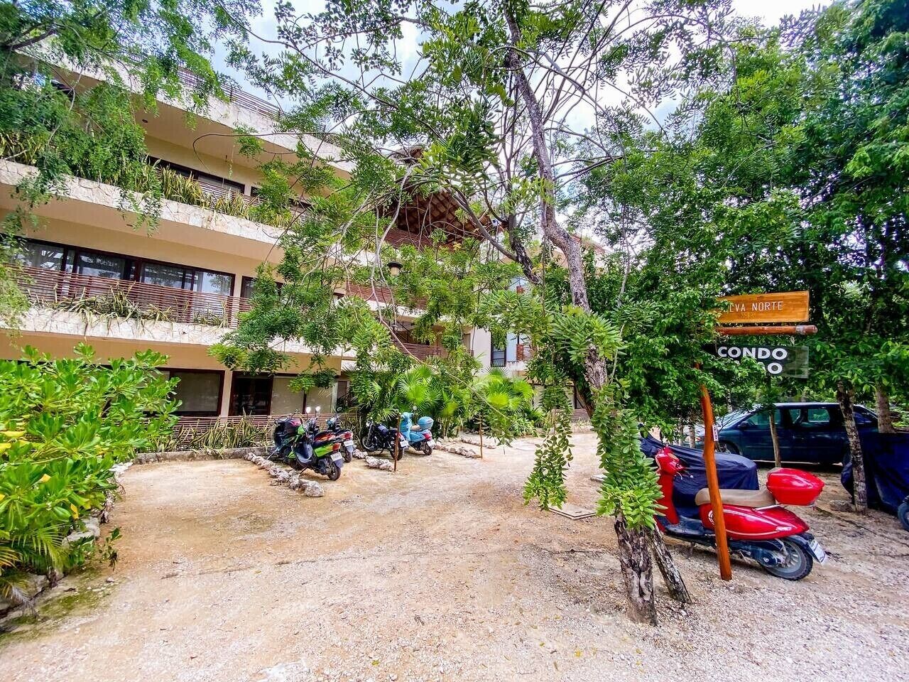 A building with multiple floors, outdoor parking, and a sign indicating 'Condo.'