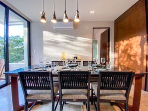 A dining area with a glass table, chairs, and pendant lighting. - 1BR Retreat near Aldea Zama with Pool (Tulum)