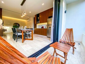 A modern kitchen with wooden cabinets, a dining area with a table and chairs, and a wooden bench. - 1BR Retreat near Aldea Zama with Pool (Tulum)