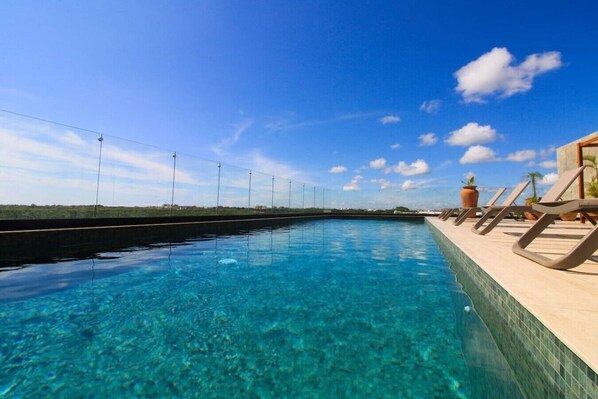 Ein klares Schwimmbecken mit Liegestühlen und Blick auf den Horizont.