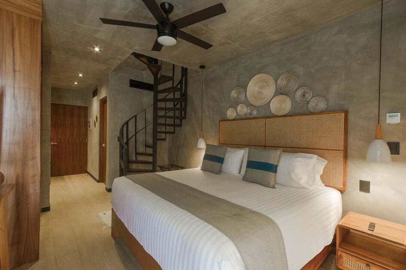 Een slaapkamer met een bed, een plafondventilator, een trap en decoratie aan de muur.