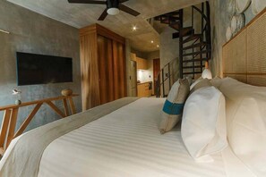 Ein Schlafzimmer mit Bett, Deckenventilator, Fernseher, Holzmöbeln und einer Treppe.