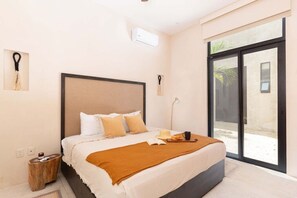 A bedroom with a bed, bedside table, lamp, and a view through a sliding door. - Manor: Apt in Aldea Zama with pool (Tulum)