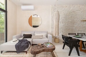 A modern living room with a sofa, coffee table, and dining area. - Manor: Apt in Aldea Zama with pool (Tulum)