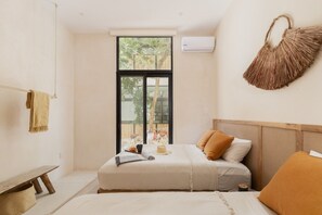 A bedroom with a large window, a bed with white bedding, a bedside table, and a hanging basket. - Manor: Apt in Aldea Zama with pool (Tulum)