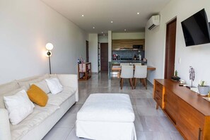 A modern living room with a sofa, ottoman, and a dining area with chairs and a table. - Spacious Apt with 2BR and Pool in Cancún (Cancún)