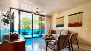 A spacious living area with a sofa, chairs, a coffee table, a decorative vase, and a view of an outdoor patio. - Sabor a Miel: Two seaside apartments (Playa del Carmen)