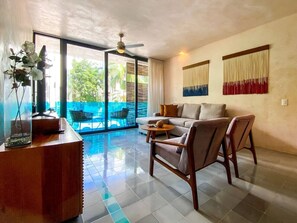 Ein großzügiger Wohnbereich mit Sofa, Sesseln, einem Couchtisch, einer dekorativen Vase und Blick auf eine Außenpatio.