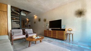 A modern living room with a staircase, a flat-screen TV, and a pool area. - Sabor a Miel: Two seaside apartments (Playa del Carmen)