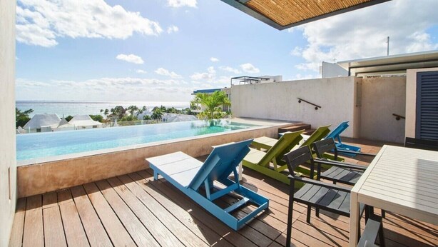 A rooftop pool with lounge chairs and a view of the ocean. - Sabor a Miel: Two seaside apartments (Playa del Carmen)