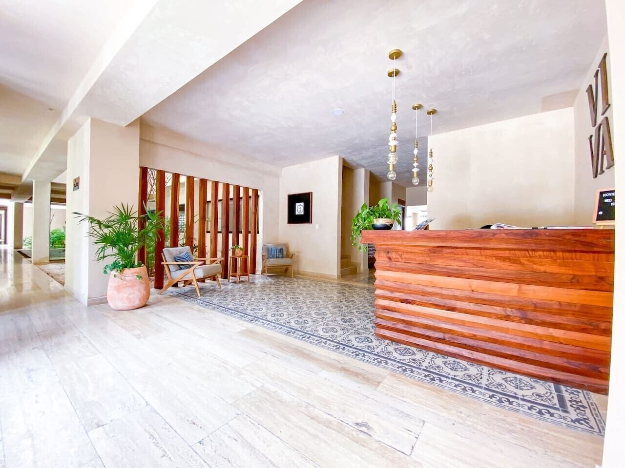 Un hall d’entrée spacieux, doté d’un comptoir de réception en bois, d’un sol à motifs et d’un jardin vertical.