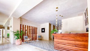 Un'ampia hall con scrivania in legno per la reception, pavimento decorato e giardino verticale.