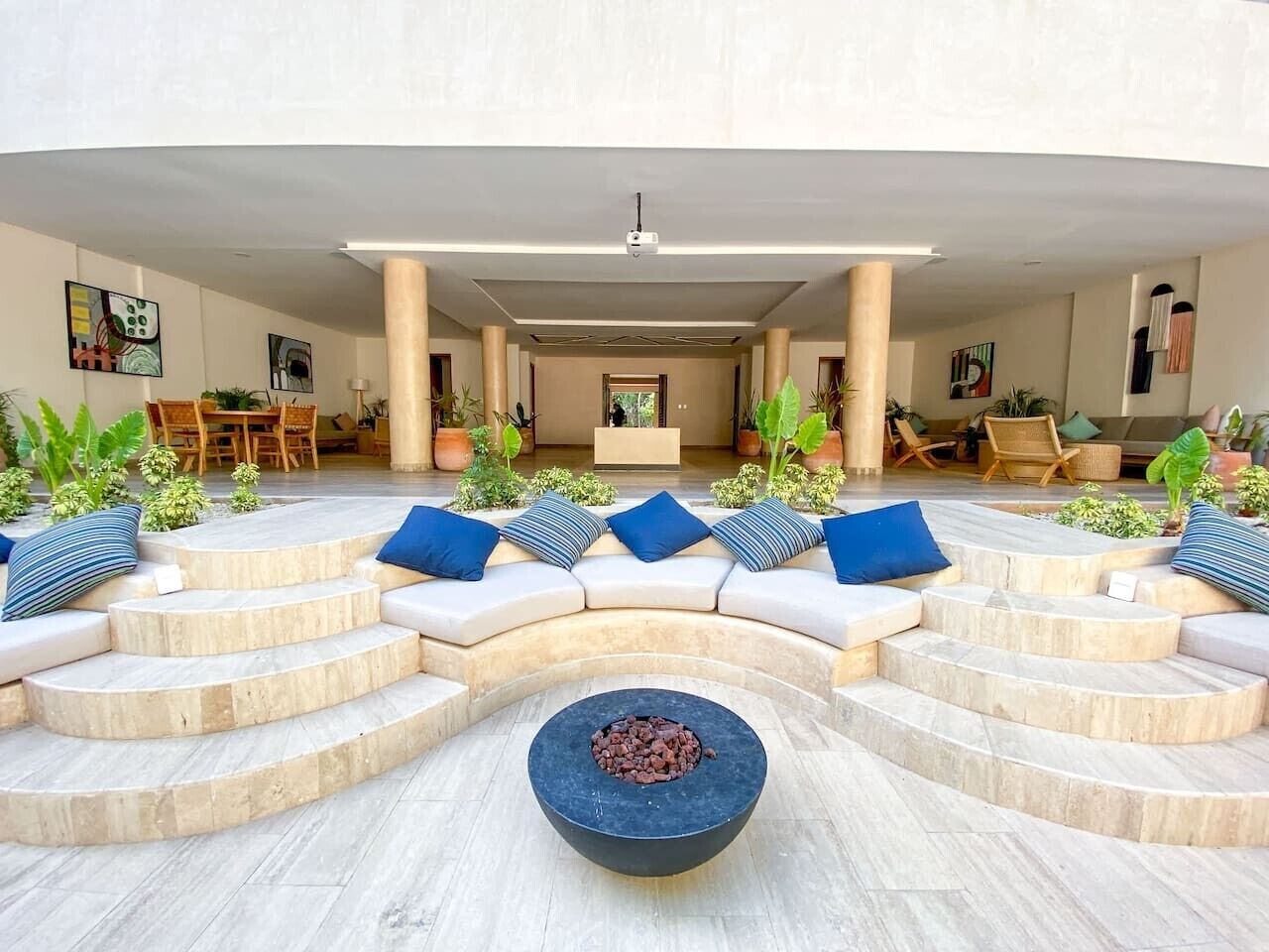 Un espace extérieur moderne, aménagé avec un canapé incurvé, un foyer central et des plantes en pot.