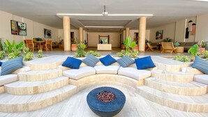 Una zona relax esterna moderna con un divano ad arco, un braciere al centro e piante in vaso.